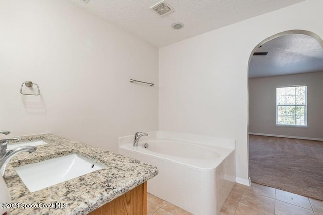 bathroom with a bathtub, tile patterned floors, a textured ceiling, and vanity