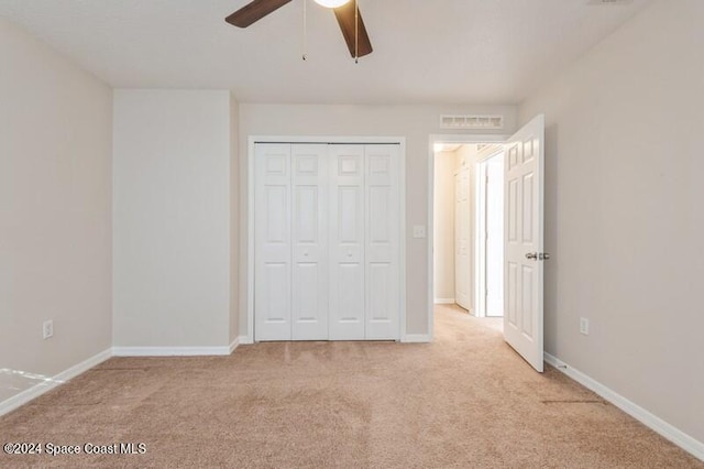 unfurnished bedroom with a closet, light colored carpet, and ceiling fan