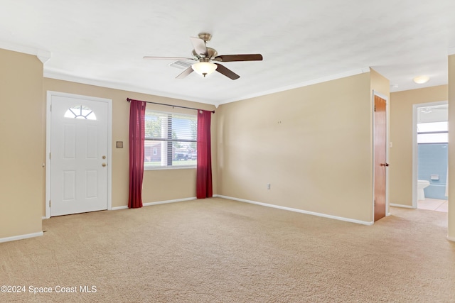 carpeted foyer with ornamental molding and ceiling fan