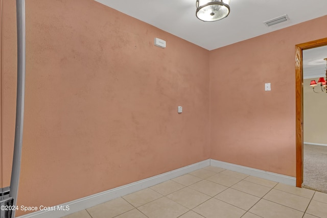 tiled empty room featuring a chandelier