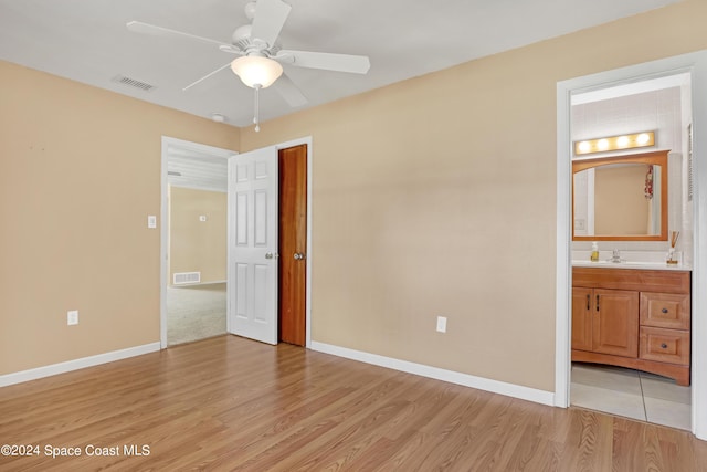 unfurnished bedroom featuring sink, light hardwood / wood-style floors, ensuite bathroom, and ceiling fan