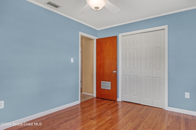 unfurnished bedroom featuring crown molding, hardwood / wood-style flooring, a closet, and ceiling fan