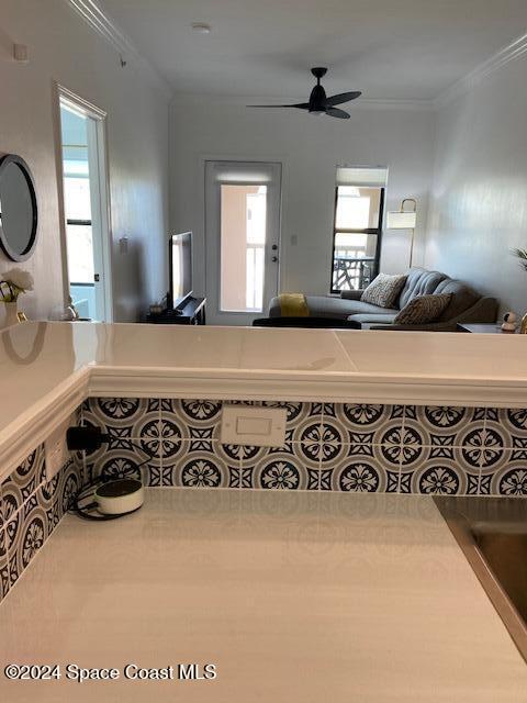 interior space with ceiling fan and ornamental molding