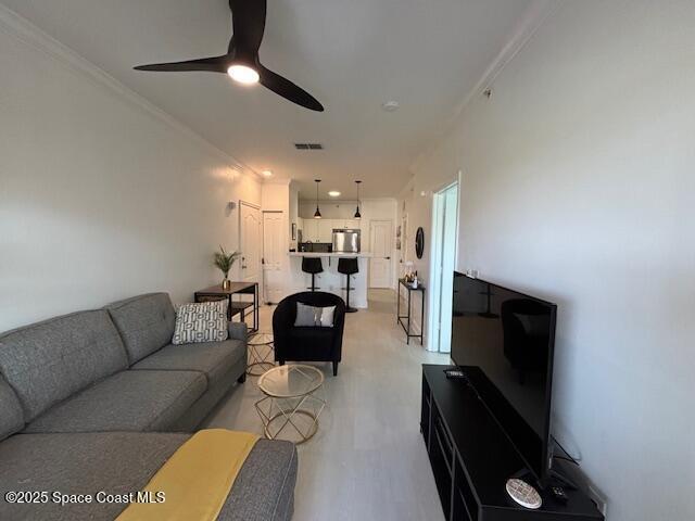 living room with ceiling fan and crown molding