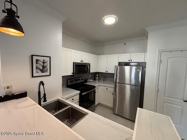 kitchen featuring white cabinets, appliances with stainless steel finishes, and decorative light fixtures