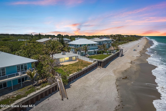 aerial view at dusk with a beach view and a water view