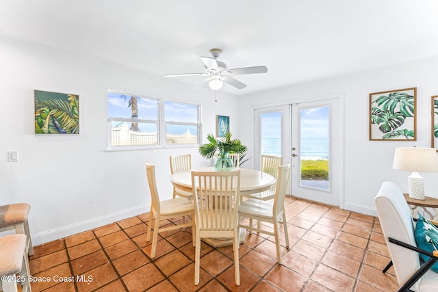 dining space featuring french doors, ceiling fan, and a water view