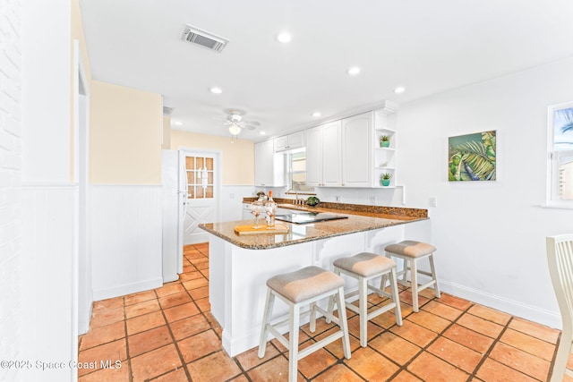 kitchen with white cabinetry, sink, dark stone countertops, white fridge, and kitchen peninsula