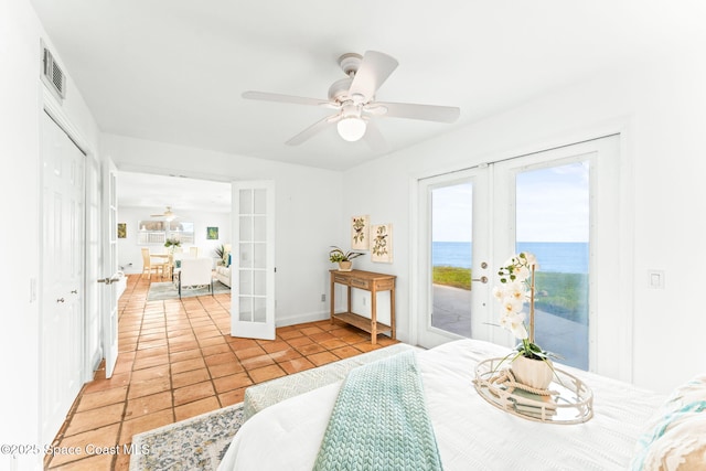 tiled dining room featuring french doors, ceiling fan, and a water view