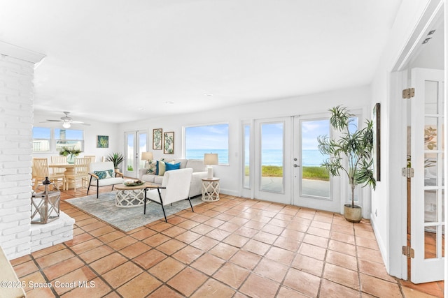 unfurnished living room with a water view, light tile patterned floors, ceiling fan, and french doors