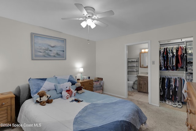 carpeted bedroom with a closet, ensuite bath, and ceiling fan