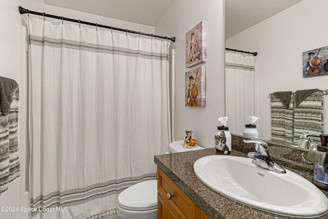 bathroom featuring a shower with curtain, vanity, toilet, and a textured ceiling