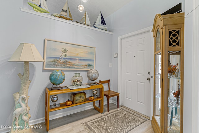 foyer entrance with light wood-type flooring and lofted ceiling