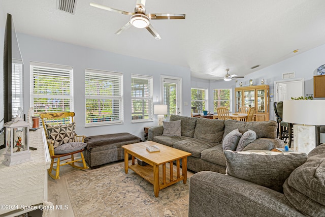 living room with light hardwood / wood-style flooring, a wealth of natural light, lofted ceiling, and ceiling fan