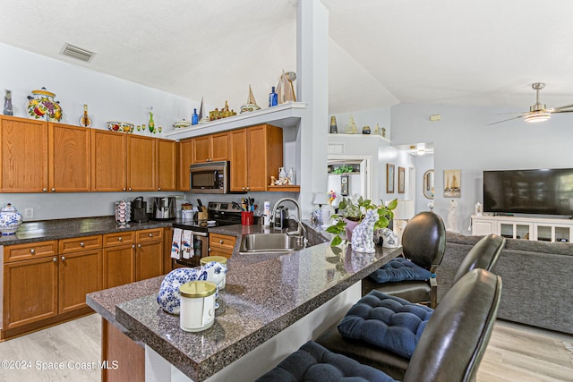 kitchen with sink, a breakfast bar area, ceiling fan, light wood-type flooring, and stainless steel appliances