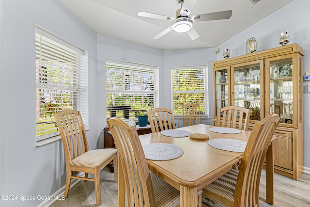 dining space with vaulted ceiling, ceiling fan, a textured ceiling, and light wood-type flooring