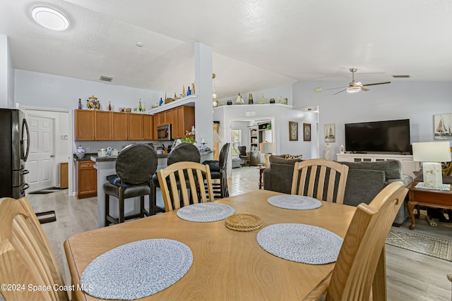 dining space with ceiling fan, lofted ceiling, and light hardwood / wood-style flooring