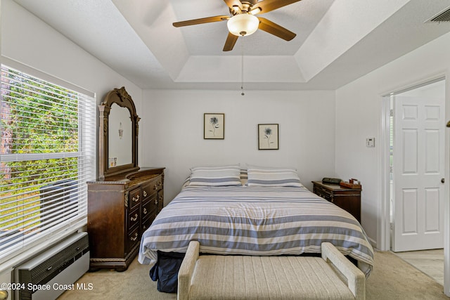 carpeted bedroom featuring a wall mounted air conditioner, ceiling fan, a raised ceiling, and a textured ceiling