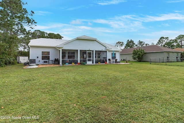 back of property with a patio area, a sunroom, and a yard