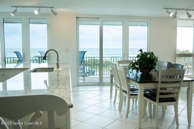 dining room with sink, light tile patterned floors, and a water view