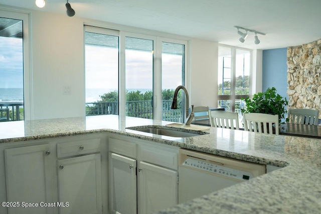 kitchen with sink, white cabinetry, dishwasher, and light stone counters