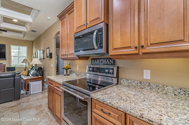 kitchen with light stone countertops, coffered ceiling, stainless steel appliances, beamed ceiling, and crown molding