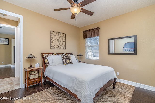 bedroom with ceiling fan, a textured ceiling, and dark hardwood / wood-style flooring