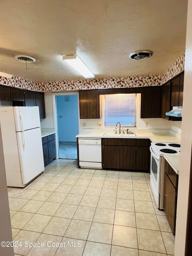 kitchen with sink, range hood, a textured ceiling, white appliances, and light tile patterned floors