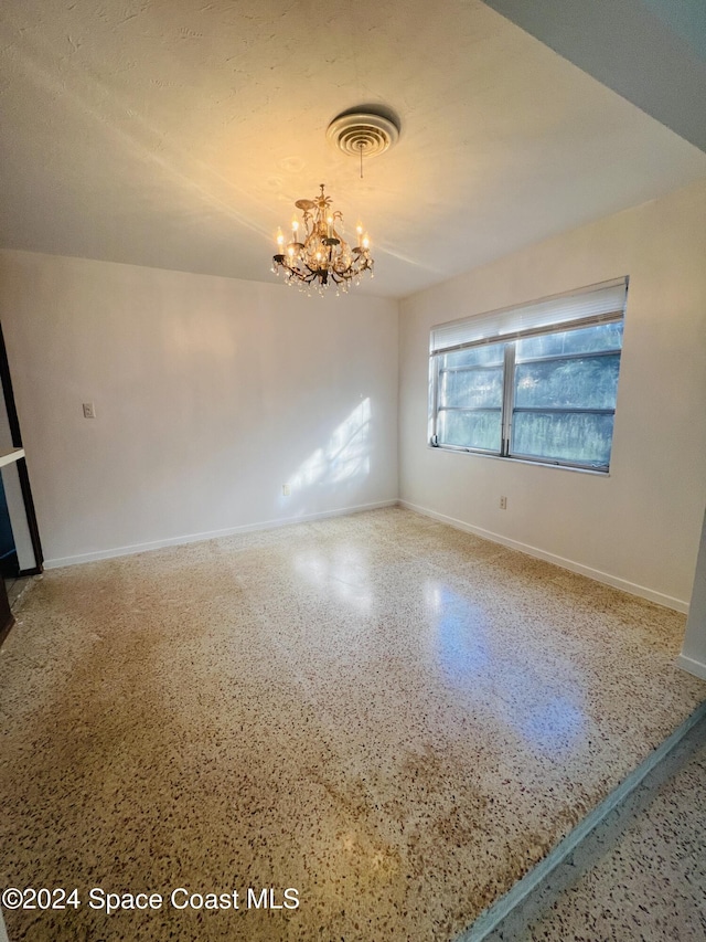 spare room featuring an inviting chandelier