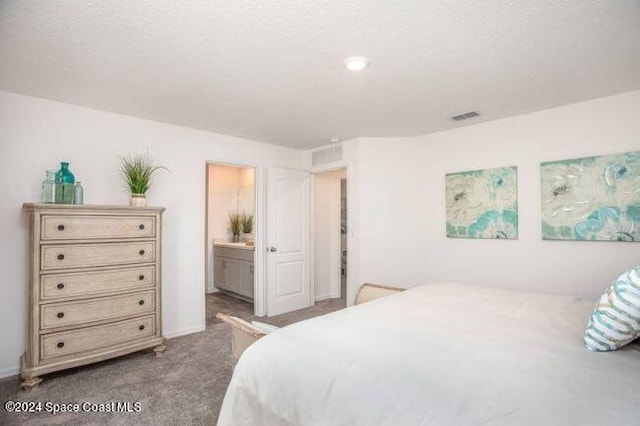 bedroom with ensuite bath, visible vents, and carpet