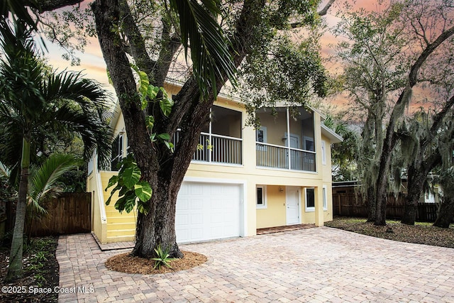 view of front of property featuring decorative driveway, stucco siding, fence, a balcony, and a garage