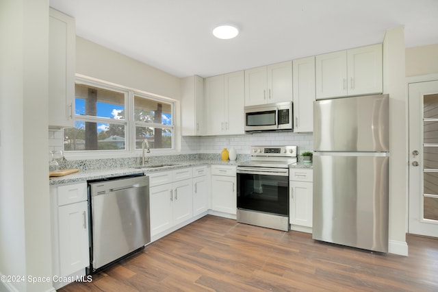 kitchen featuring sink, dark hardwood / wood-style flooring, white cabinetry, stainless steel appliances, and light stone counters