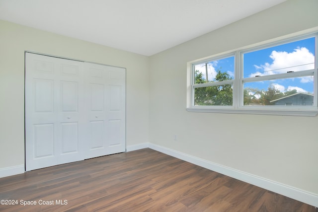 unfurnished bedroom with dark wood-type flooring and a closet