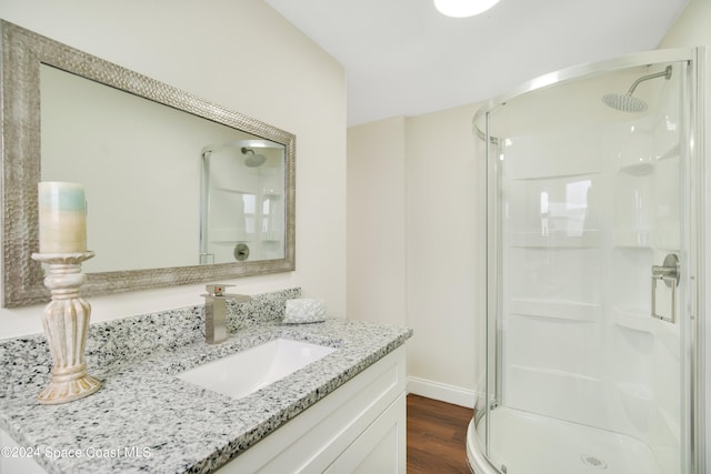 bathroom with vanity, a shower with shower door, and hardwood / wood-style floors