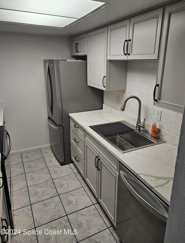 kitchen featuring light tile patterned flooring, gray cabinets, sink, and appliances with stainless steel finishes