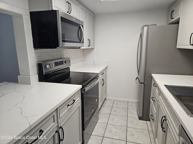 kitchen featuring sink, light stone counters, appliances with stainless steel finishes, tasteful backsplash, and light tile patterned floors