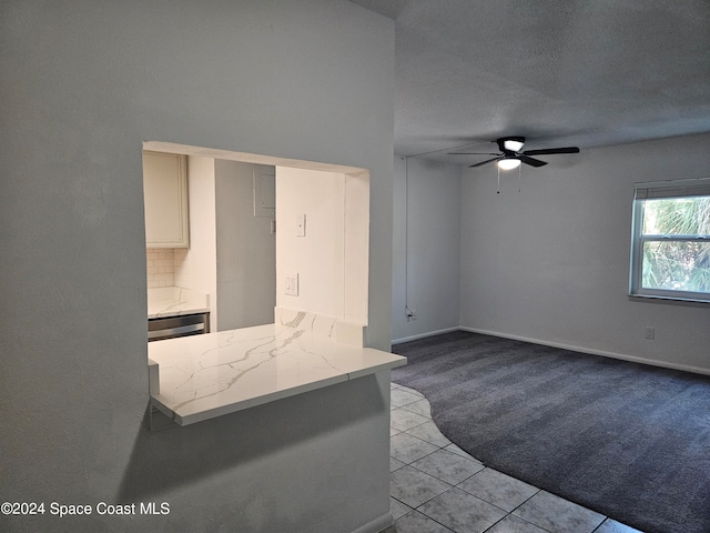 kitchen featuring ceiling fan, a textured ceiling, and light tile patterned floors