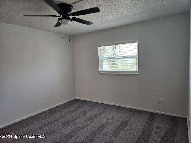 unfurnished room with ceiling fan, a textured ceiling, and dark carpet