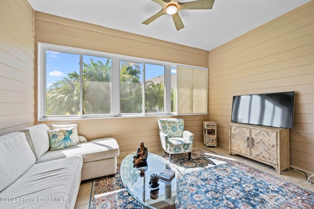 living room with ceiling fan and wood walls