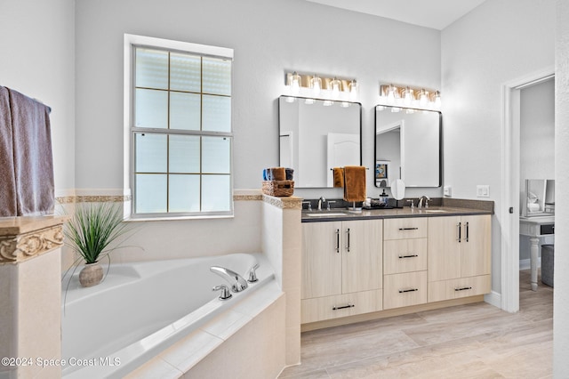 bathroom with vanity, plenty of natural light, tiled tub, and hardwood / wood-style floors