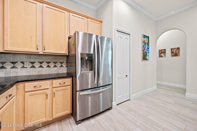 kitchen with stainless steel refrigerator with ice dispenser, dark stone countertops, and light brown cabinetry