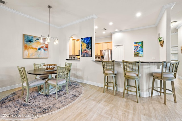 dining area with an inviting chandelier, ornamental molding, and light hardwood / wood-style floors