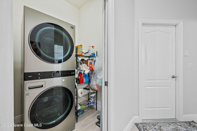 washroom with light hardwood / wood-style flooring and stacked washing maching and dryer