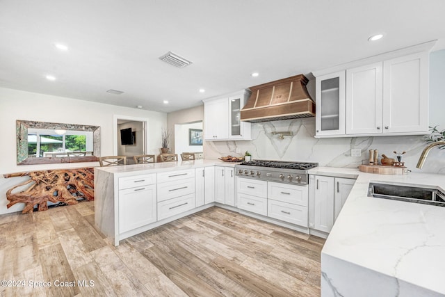 kitchen with white cabinetry, custom range hood, and stainless steel gas cooktop