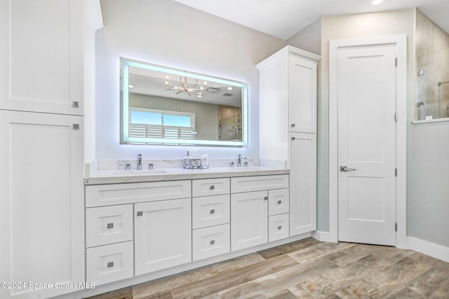 bathroom featuring a tile shower, vanity, wood-type flooring, and a notable chandelier