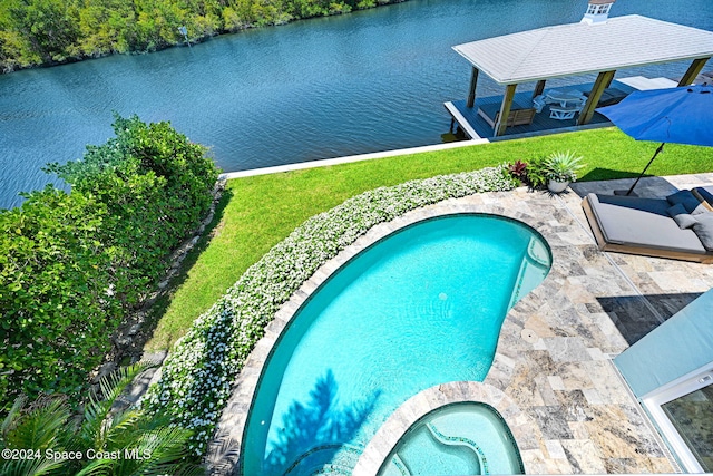 view of swimming pool with a patio area, a water view, a yard, and an in ground hot tub