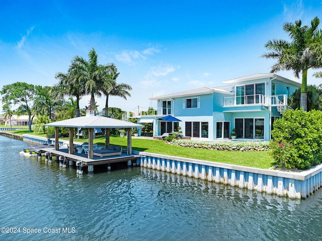 back of house featuring a water view, a yard, and a balcony