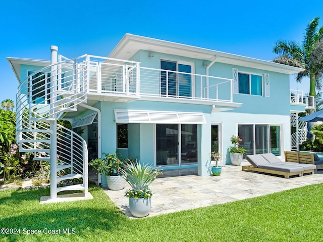 back of property with a lawn, a patio area, and a balcony