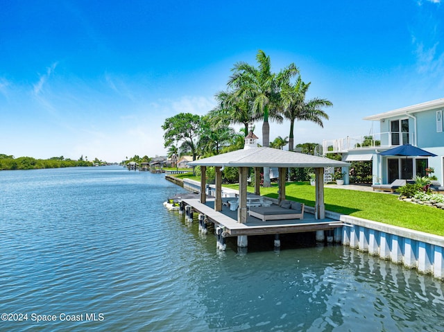 view of dock with a lawn and a water view