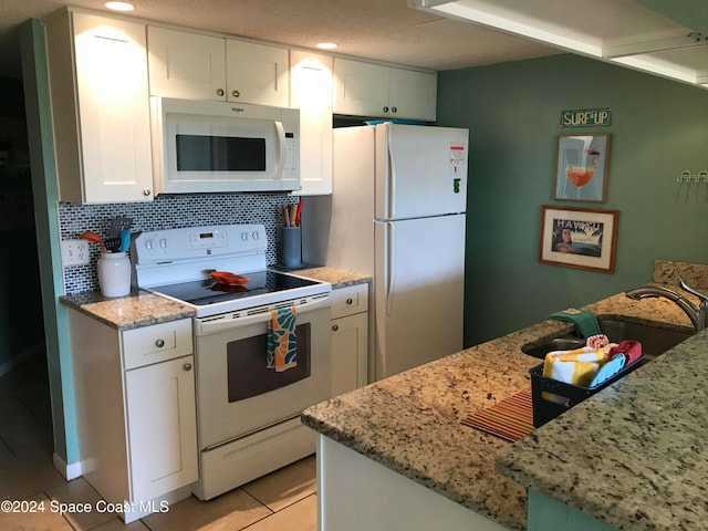 kitchen featuring white appliances, sink, light stone countertops, tasteful backsplash, and white cabinetry